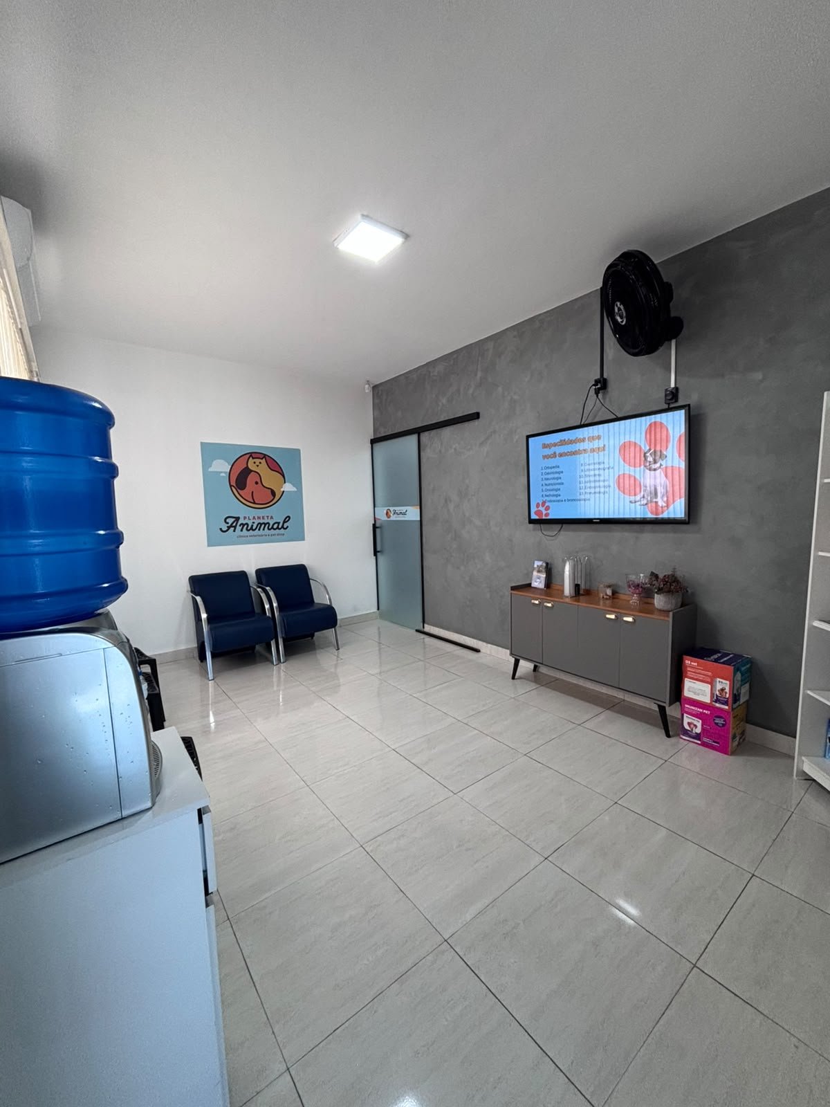Sala de espera da clínica com cadeiras e TV